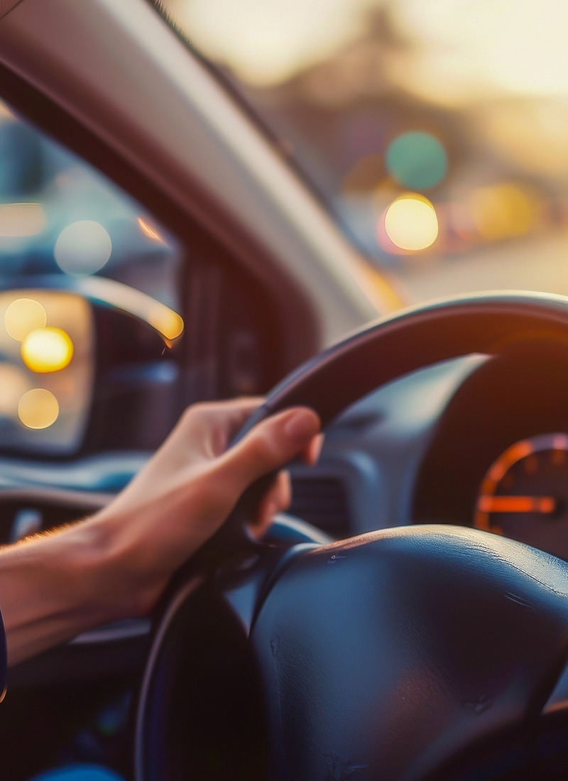 a hand gripping a steering wheel while driving on a sunny day emphasizing control and focus in a car driving scenario